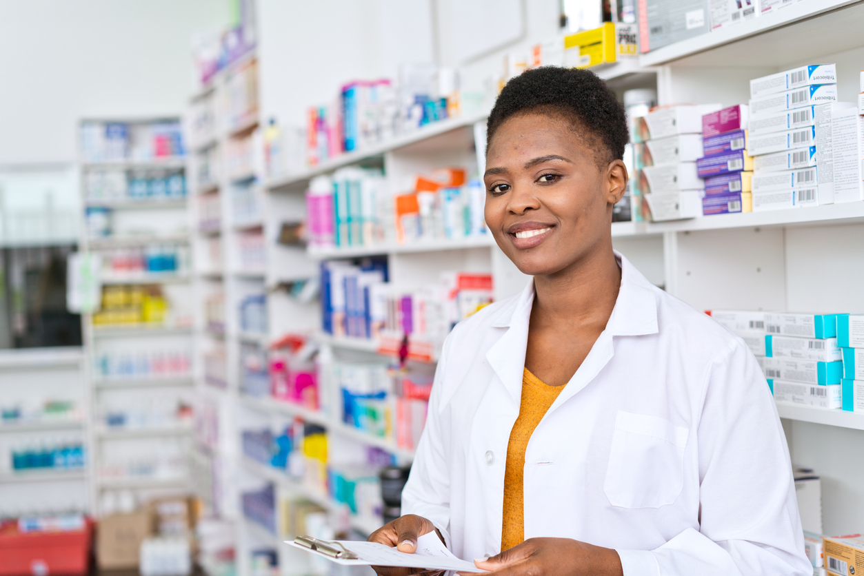 A young pharmacist standing in front of medicine shelves